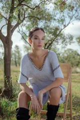 Minivestido tejido en lurex plateado, con escote en V y mangas cortas. Presenta detalle de bordado en el escote y mangas.