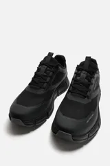 Zapatillas deportivas negras con capellada de tejido técnico transpirable y suela gruesa.