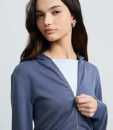 Campera corta de modal color azul, con capucha fija, mangas largas y cierre frontal de cremallera.