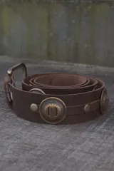 Cinturón marrón de cuero vacuno encerado, con hebilla metálica dorada y apliques de monedas metálicas con diseño floral.
