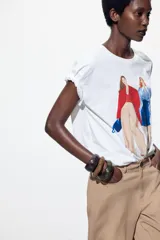 Camiseta blanca de algodón con estampado de dos figuras femeninas.