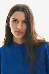 Blusa azul eléctrico de algodón con cuello mao, botones frontales, manga 3/4 abullonada con bordado calado y puños festoneados.