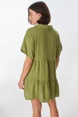 Vestido corto celeste de lino, con cuello tipo polo con detalle de puntilla, mangas cortas y falda escalonada con volantes.