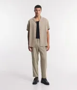 Camisa boxy masculina de viscosa color beige, con mangas cortas, cuello camisero y abotonadura frontal.