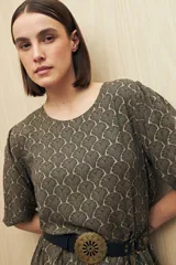 Vestido corto con estampado animal print en tonos beige, negro y marrón. Tiene corte holgado, mangas cortas y falda con vuelo.