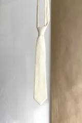 Corbata delgada de lana con forro interno y diseño a cuadros en tonos marrón y beige.