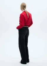 Pantalón de jean negro de corte wide leg, tiro alto y largo hasta el tobillo. Presenta trabillas, cinco bolsillos y bajo deshilachado. Cierre frontal con cremallera y botón.