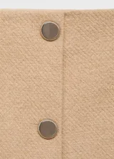 Falda corta color beige con botones frontales y tejido texturizado.