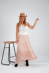 Pollera larga de color rosa pálido, con corte en capas y cintura con lazo ajustable.
