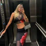 Conjunto de top corto y falda larga de tul negro con estampado de flores rojas.
