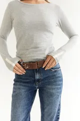 Cinto marrón de cuero con hebilla metálica y tachas decorativas.