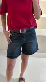 Bermuda de jean azul con ruedo desflecado, bolsillos delanteros y traseros, y bordado en uno de los bolsillos traseros.