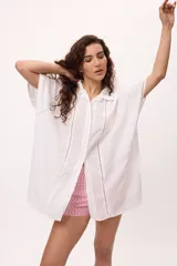 Camisa blanca de manga corta con cuello clásico, corte holgado y detalle de calado vertical en el frente.