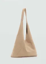 Bolso tote color beige de piel serraje, con forro interior de algodón, asa larga y cierre de botón magnético y cremallera.