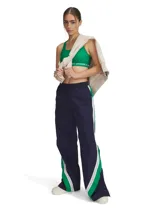 Pantalón deportivo Under Armour para mujer, confeccionado en tejido ligero con textura arrugada y paneles laterales a presión. Diseño de corte holgado con cintura elástica y logo de la marca bordado en verde.