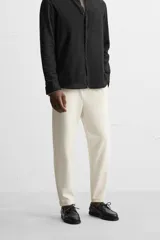 Pantalón negro de corte cropped, con cintura elástica ajustable con cordón, bolsillos laterales y traseros de vivo. El bajo tiene terminación con vuelta.