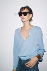 Jersey celeste de punto liso, con cuello redondo, manga larga y botones delanteros.