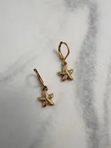 Par de aros dorados con forma de estrella de mar colgando de un aro pequeño con cierre tipo gancho.