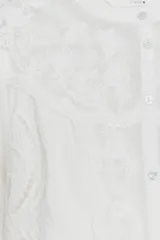 Camisa blanca de cuello redondo y manga larga con bordados combinados a tono y cierre frontal con botones.