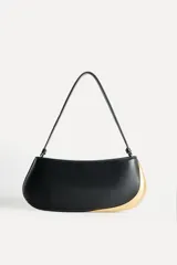 Bolso de hombro alargado color crema, con asa corta y detalle metálico dorado en un lateral. Tiene un bolsillo interior con cremallera y cierre principal con cremallera.