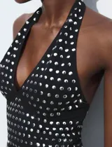 Top negro con cuello halter y espalda descubierta, con apliques de tachas plateadas.
