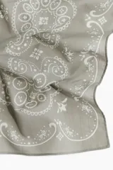 Pañuelo cuadrado gris con estampado de flores y arabescos en blanco.