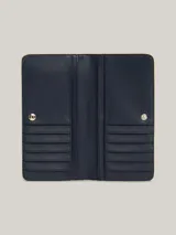Billetera estilizada grande color beige, con cierre a presión y múltiples compartimentos para billetes y tarjetas, destacándose la insignia del monograma TH.