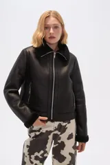 Campera corta negra de cuero sintético con cuello y puños de piel sintética negra, cierre frontal con cremallera y bolsillos laterales con cremallera.