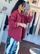 Chaqueta de jean oversize color rojo, con cuello clásico, cierre frontal con botones y mangas largas con puños abotonados.