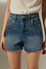 Short de jean azul con tachas plateadas y ruedo desflecado.