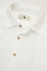 Camisa blanca de manga larga confeccionada en lino 100%, con calce recto y relajado. Presenta frente abotonado con botones de coco con logo y parche con logo de la marca.