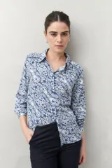 Camisa de manga larga con estampado paisley en tonos azul y blanco, cuello camisero y cierre frontal con botones.