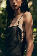 Vestido midi negro de escote recto y tirantes finos con abalorios. Tiene abertura frontal y cierre trasero con cremallera oculta.