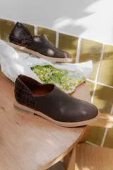 Zapato bajo color marrón con detalle de cuero texturizado en el talón.