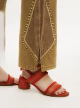 Pantalón de jean gris oscuro con corte oxford y apliques metálicos alrededor de los bolsillos y en la parte externa.