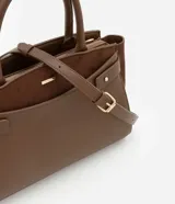 Cartera satchel mediana color marrón, confeccionada en cuero sintético con detalles en gamuza. Cuenta con asas medianas, cierre de cremallera y detalles metálicos dorados. Incluye correa extraíble y regulable.