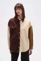 Sobrecamisa de pana con diseño color block en tonos marrón oscuro, beige y camel. Presenta cuello camisero, botones frontales, un bolsillo de parche en el pecho izquierdo y bordes deshilachados en el ruedo y puños.