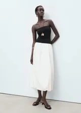 Vestido midi de algodón, con corpiño negro tipo palabra de honor ajustado y falda blanca con volumen estilo globo.