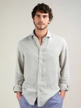 Camisa de hombre color gris claro, confeccionada en lino, de corte regular fit, con cuello italiano, cierre con botones, manga larga terminada en puño simple y logo bordado en el pecho.