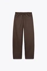 Pantalón marrón tipo barrel, de tiro medio con cintura elástica ajustable con lazada, bolsillos laterales y falsos bolsillos de vivo en la espalda.