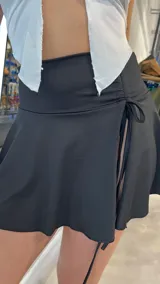 Minifalda negra de lycra, tiro bajo, corte ajustado y largo a la cadera.