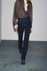 Pantalón de jean azul oscuro, de tiro bajo, corte slim fit y bootcut. Con cinco bolsillos y cierre frontal con cremallera y botón.