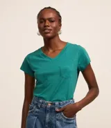 Blusa blanca de algodón con cuello en V, manga corta y bolsillo frontal.