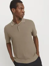 Polo de punto color beige, con cuello clásico, mangas cortas y cierre con botones.