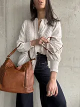 Camisa color beige de lino con detalles de broderie en el frente y mangas largas con puños elásticos.