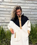 Buzo tipo poncho de polar color crudo con bloque superior en negro y detalles en beige.