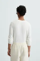 Jersey color topo de corte amplio, tejido en hilatura con mezcla de viscosa. Tiene cuello redondo, manga larga y terminaciones en rib.