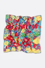 Pañuelo cuadrado de poliéster reciclado con estampado de flores multicolores y logo en acuarela sobre fondo azul.