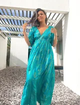 Túnica larga color turquesa con estampado de arabescos dorados, escote en V y mangas cortas.