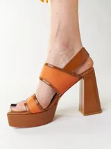 Sandalias de plataforma color naranja con detalles en marrón. Tienen tiras anchas sobre el empeine y el tobillo, y un tacón cuadrado alto.